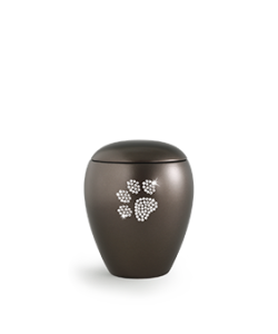 Matte, dunkle Urne mit einem mit Juwelen besetzten Pfotenabdruck auf der Vorderseite, vor einem schlichten Hintergrund. Aurora Tierkrematorium