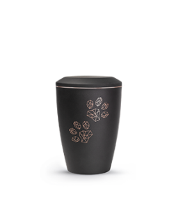 Eine schwarze Urne mit geometrischen Pfotenabdrücken auf der Vorderseite, vor einem schlichten Hintergrund. Aurora Tierkrematorium