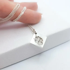 Ein Finger mit einer silbernen Halskette und einem Pfotenabdruck-Anhänger. Aurora Tierkrematorium