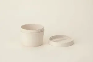 Ein schlichter, runder, weißer Behälter mit passendem Deckel auf neutralem Hintergrund. Aurora Tierkrematorium