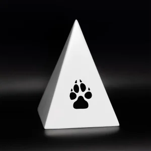 Ein weißes pyramidenförmiges Objekt mit einem schwarzen Tierpfotensymbol auf einer Seite vor einem schwarzen Hintergrund. Aurora Tierkrematorium