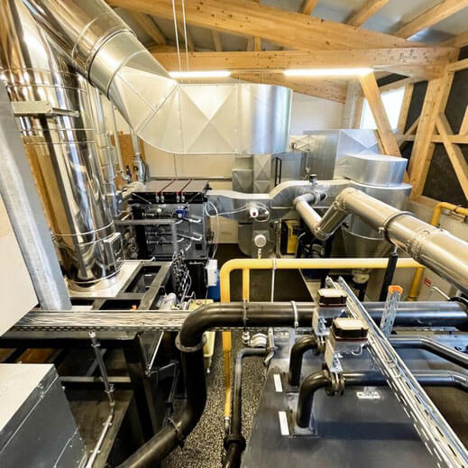 Industrielles HLK-System mit großen Metallkanälen, Rohrleitungen und Lüftungsanlagen, das in einem Gebäude mit freiliegenden Holzbalken installiert ist, wie sie im Aurora Tierkrematorium zu finden sind. Aurora Tierkrematorium