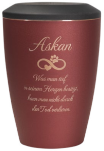 Eine rote Urne mit schwarzem Deckel trägt den Namen "Askan" und eine deutsche Inschrift mit Pfotenabdruck, die das Andenken an ein Haustier symbolisiert. Aurora Tierkrematorium