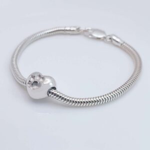 Ein Silberarmband mit Schlangenkette und einem herzförmigen Anhänger mit eingraviertem Pfotenabdruck. Aurora Tierkrematorium